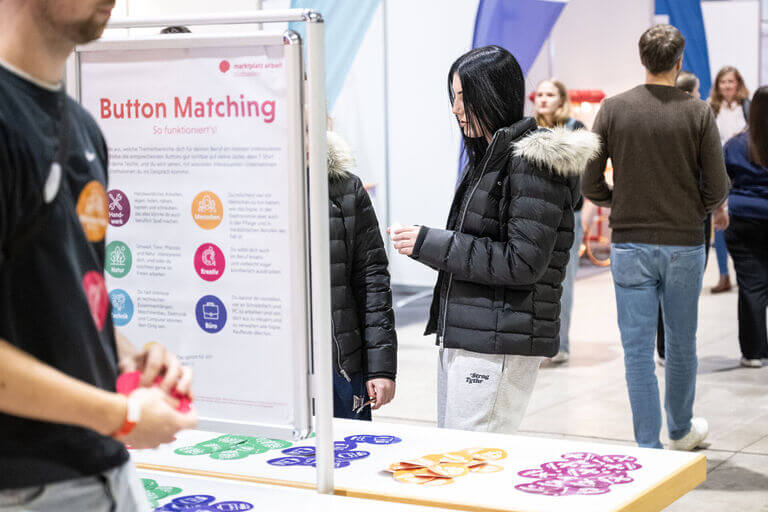 Eindrücke von der Messe für Karriere, Studium, Aus- und Weiterbildung marktplatz arbeit südbaden in Freiburg im November 2024. Auszubildende, Schüler und Berufstätige informieren sich zum Thema Berufseinstieg und Karriere bei Unternehmen aus dem Raum Freiburg und Südbaden. Hier nutzen Besucher das Button Matching als einfache Möglichkeit zur Kontaktanbahnung.